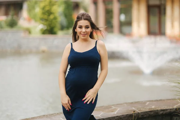 Hermosa joven alegre embarazada de pie en el fondo de la fuente — Foto de Stock