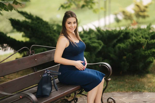 Femme enceinte assise sur un banc près du lac — Photo