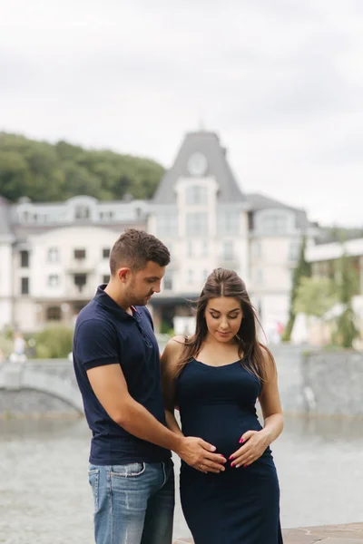 Schwangere und ihr Ehemann umarmen sich und lächeln — Stockfoto