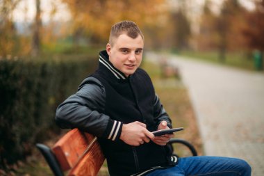 Siyah ceketli genç bir çocuk bir tablet kullanır