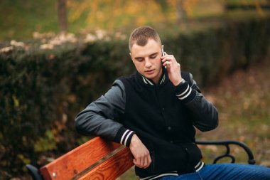 Siyah ceketli genç bir çocuk telefon kullanır