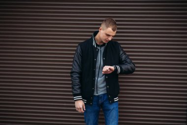 Bir arka plan koyu çizgili duvar ve yağma seyretmek siyah ceketli genç bir çocuk