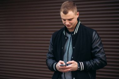 Bir arka plan koyu çizgili duvar siyah ceketli genç bir çocuk telefon kullanır