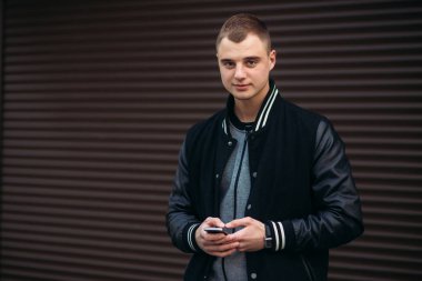 Bir arka plan koyu çizgili duvar siyah ceketli genç bir çocuk telefon kullanır