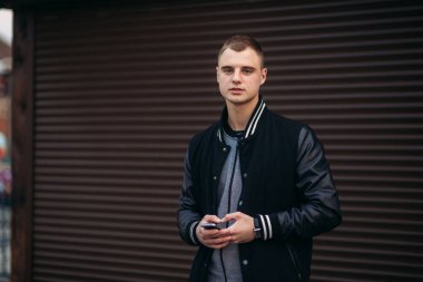 Bir arka plan koyu çizgili duvar siyah ceketli genç bir çocuk telefon kullanır