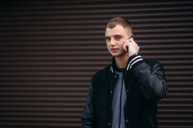 Bir arka plan koyu çizgili duvar siyah ceketli genç bir çocuk telefon kullanır