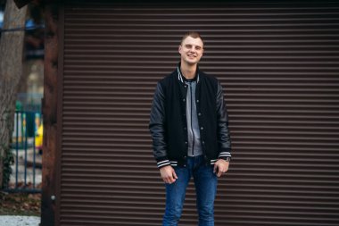 Bir arka plan koyu çizgili duvar siyah ceketli genç bir çocuk