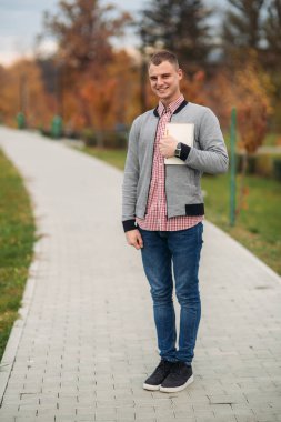 Komik öğrenci Not defteri ile. Adam tribünde park ve gülümseme