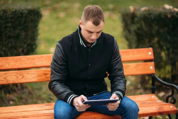 Un joven con una chaqueta negra usa una tableta —  Fotos de Stock
