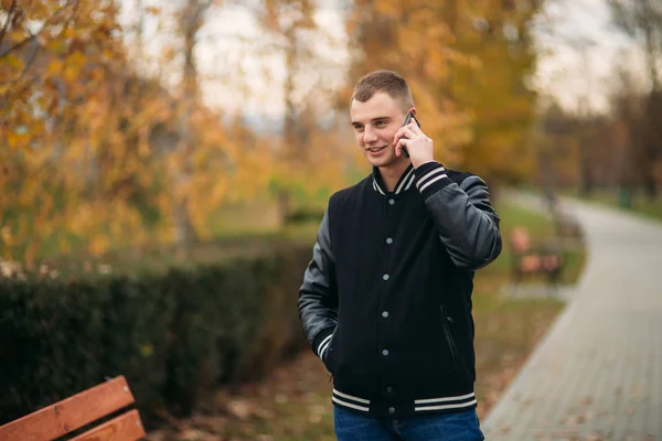 Un joven con una chaqueta negra usa el teléfono — Foto de Stock