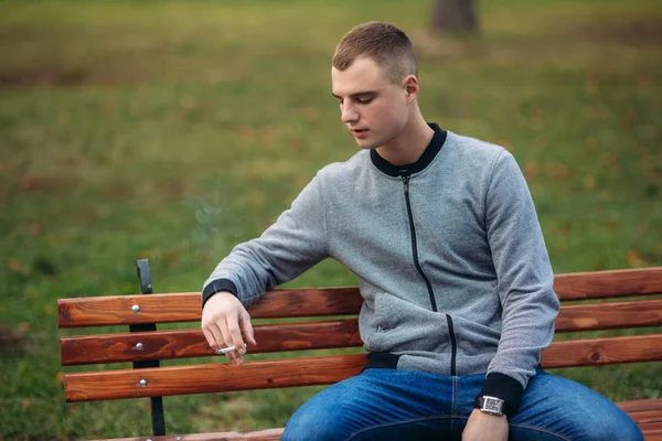Un joven fuma cigarrillos en el parque — Foto de Stock