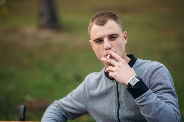 Молодий хлопець курить сигарету в парку — стокове фото
