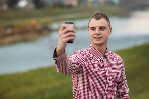 Elegante ragazzo in una camicia chekered utilizzando un telefono — Foto Stock