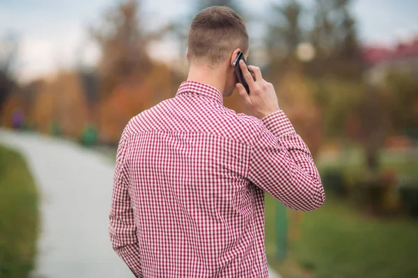 Stylish guy in a chekered shirt using a phone — Stock Photo, Image