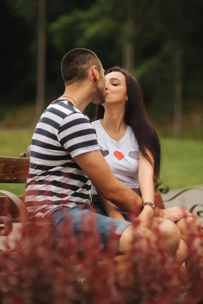 Un mec et une fille s'amusent dans une ambiance romantique et s'assoient sur le banc — Photo