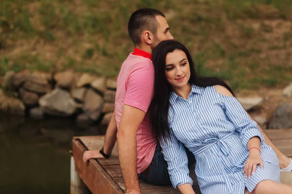 Mann und Mädchen genießen einander in romantischer Atmosphäre, sitzen auf der Seebrücke — Stockfoto