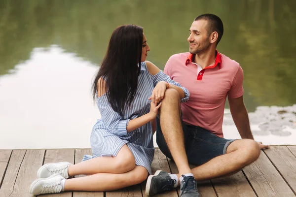 Facet i dziewczyna cieszyć się sobą w romantycznej atmosferze, siedzi na molo — Zdjęcie stockowe