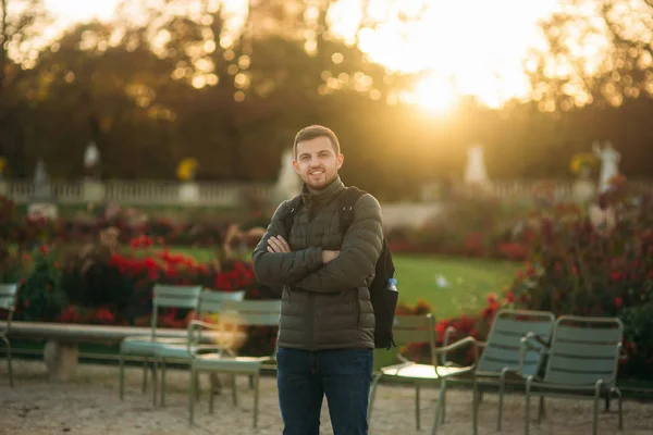 Bello uomo con zaino in posa per fotografo nel parco — Foto Stock