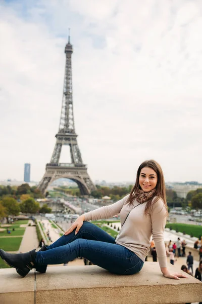 Linda senhora sist na fronteira contra a torre eiffel. Senhora sorrir e se divertir — Fotografia de Stock