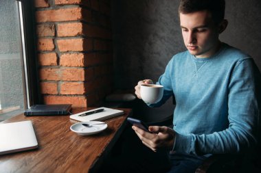 Genç bir iş çalışan ve bir kafede kahve içme ve not defterinde bir şey yazmak