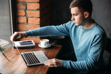 Bir kafede dizüstü bilgisayar ile genç programcı pencerenin oturur