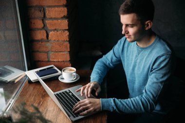 Bir kafede dizüstü bilgisayar ile genç programcı pencerenin oturur