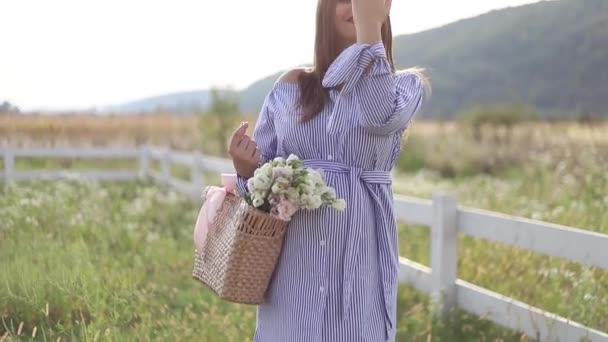 Привлекательная беременная женщина позирует перед камерой и улыбается. Женщина стоит на природе и ходит мыслеполе рядом с фермой. медленное движение HD — стоковое видео