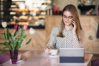 Genç kız programer kafede dizüstü bilgisayar ve telefon kullanın. çalışma öğrenci