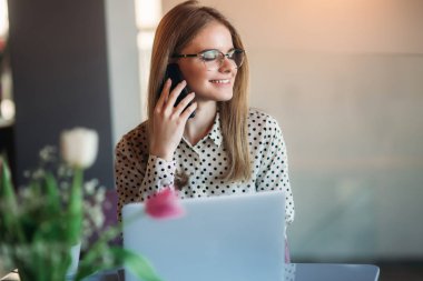 Çekici genç bayan ara birisi kafe içinde belgili tanımlık laptop üzerinde çalışıyor ve telefon