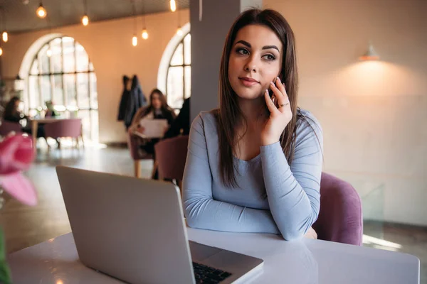 Senhora de negócios sentado no café e trabalhando em um laptop e usando telefone — Fotografia de Stock