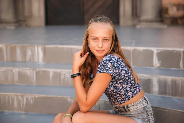 Девушка-подросток в джинсах сидит на лестнице — стоковое фото