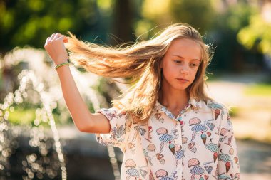 Sarışın genç kız saçını bir çeşme arka plan üzerinde ile oynarken bir sarı bluz