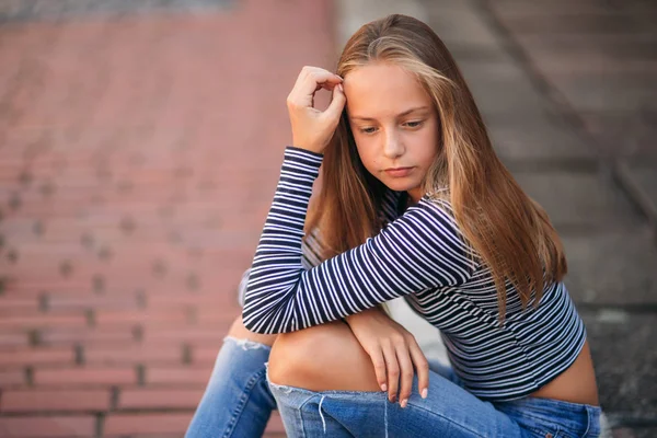 Jonge tiener houdingen voor foto. blond meisje in spijkerbroek en blouse — Stockfoto