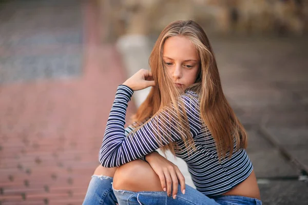 Unga tonåriga poser till fotograf. Blond flicka i jeans och blus — Stockfoto