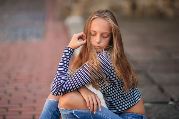 Unga tonåriga poser till fotograf. Blond flicka i jeans och blus — Stockfoto