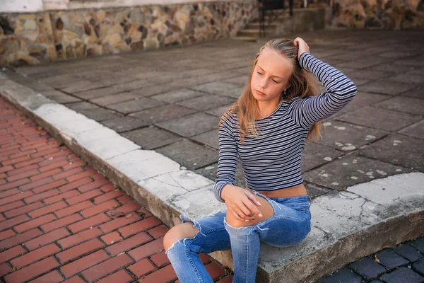 Jonge tiener poses aan fotograaf. blond meisje in spijkerbroek en blouse — Stockfoto