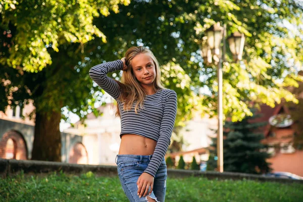 Szőke tizenéves lány csíkos blúz, a zöld fa a backgrountd — Stock Fotó