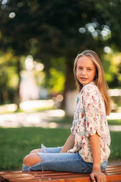 Ung tonårsflicka sitter på bänken — Stockfoto