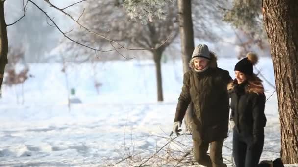 Счастливая пара играют вместе во время зимних каникул призвание на улице в снежном парке. они бегают и прыгают — стоковое видео