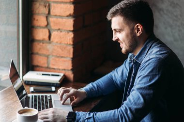 Bir sakallı bir dizüstü bilgisayar bir kafede kullanır.