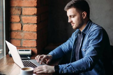 Bir sakallı bir dizüstü bilgisayar bir kafede kullanır.