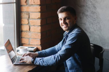 Bir sakallı bir dizüstü bilgisayar bir kafede kullanır.