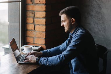 Bir sakallı bir dizüstü bilgisayar bir kafede kullanır.