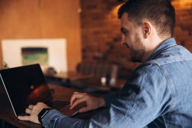 Bir kafede bir dizüstü bilgisayar üzerinde çalışan genç programcı