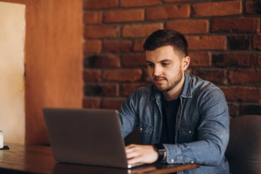 Bir kafede bir dizüstü bilgisayar üzerinde çalışan genç programcı