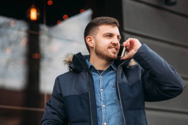 Yakışıklı bir ceketli bir telefon ayakta sokakta kullanır.