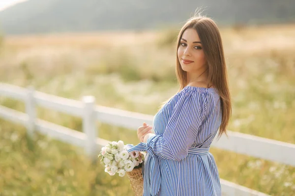 Vista de perto da bela mulher grávida no campo segurando buquê e sorriso. Relaxe na natureza — Fotografia de Stock