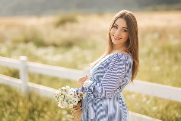 Vista da vicino di bella donna incinta in campo tenendo bouquet e sorriso. Relax nella natura — Foto Stock