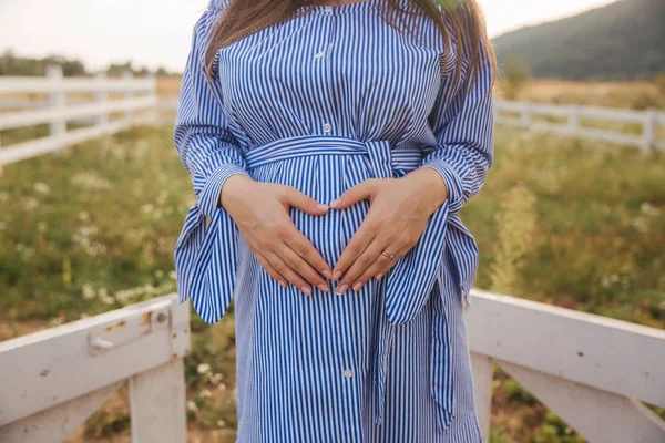 接近怀孕的腹部在自然的看法。女人捧着花束抚摸着她的腹部 — 图库照片