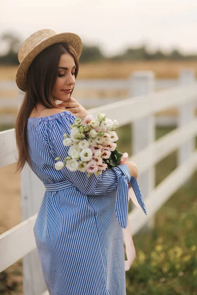 Charmante zwangere vrouw houd een boeket bloemen. Gelukkige vrouw glimlach. Toekomstige moeder in de natuur — Stockfoto